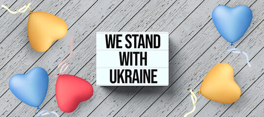 lightbox with the message WE STAND WITH UKRAINE on wooden background