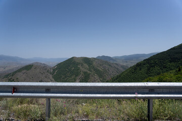 view of a large crop field from the highway where you can see the roadside barrier