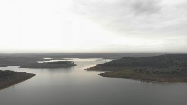 Aerial images showing the banks of a reservoir from 100 meters high. Flying over the water with the sunset in the background. cloudy day with rain clouds