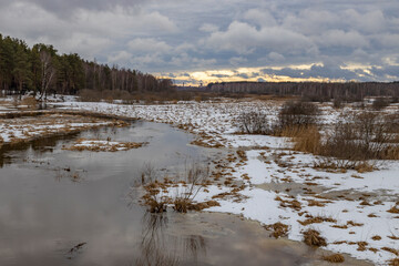 Spring flood. Evening landscape with a river and melting snow.