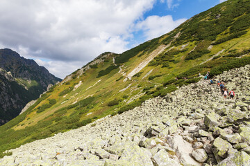 Tourists hiking in Tatra Mountains under blue cloudy sky