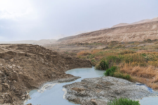 Sinkhole filled with turquoise water, near Dead Sea coastline. Hole formed when underground salt is dissolved by freshwater intrusion, due to continuing sea-level drop. . High quality photo