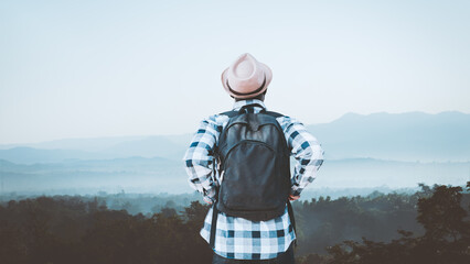 African backpack traveler man looking a sunrise ,fog and landscape on a top of a mountain