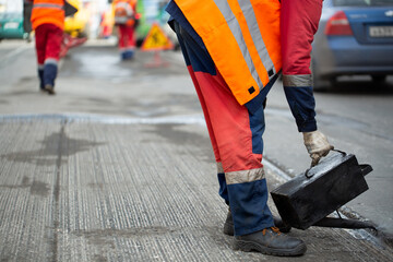 A worker pours liquid asphalt, molten bitumen from a bucket of resin.