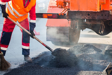 Repair of roads, highways and sidewalks. Patching. Working with a shovel falls asleep in the pit