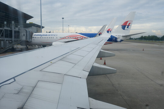 "Kuala Lumpur, Malaysia- Circa February, 2022: A picture with noise effect of Malaysia Airlines wing and aircraft from window. Rain drop insight."