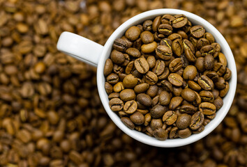Roasted coffee beans in white cup. Close up aromatic drinks 