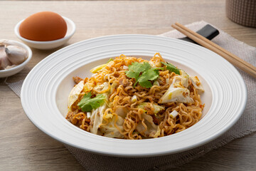 Stir fried instant noodle with canned mackerel fish,Cabbage and egg in white plate