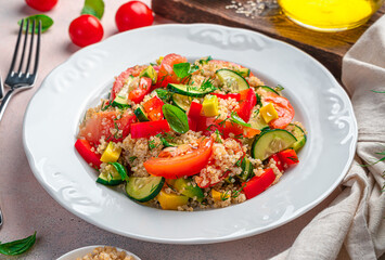 Healthy vegetable salad with quinoa and fresh herbs on a light background.