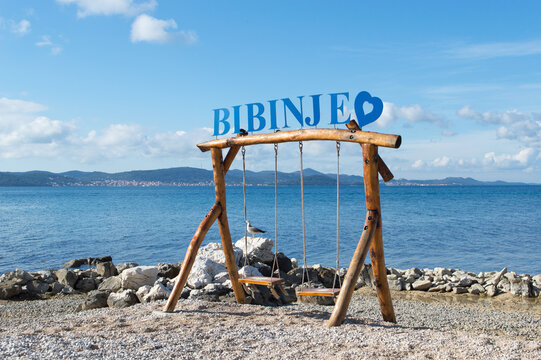 Beautiful coastal village Bibinje close to Zadar in Croatia, sign on the wooden swings on the beach with the view on the opposite island Ugljan