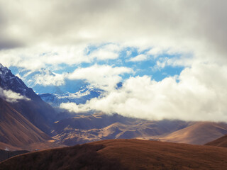 White thick clouds descended on the mountain peaks. Caucasian mountain range covered with snow at...