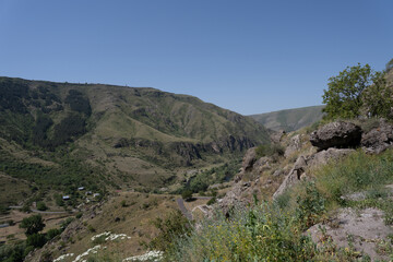 monastery in the mountains of georgia where there are caves and passages along the mountain, above them there is a blue sky.