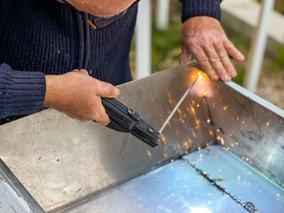 Man doing metal work using a whisk and a welding machine