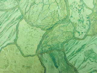 Green stone tile with stone texture and scuffs. Green vintage background with patterns.