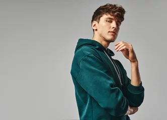 Handsome man in green hoodie isolated on gray background © kiuikson