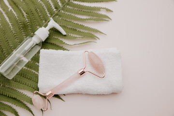 Jade face roller with towel on a fern leaf. Facecare concept