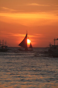 Sunset seascape with silhouette of saiboats in Boracay, Philippines.