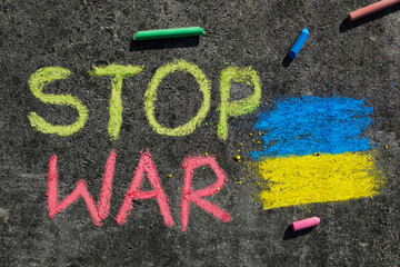 Flag of Ukraine and text STOP WAR. Chalk drawing on sidewalk.War problem and requests for peace