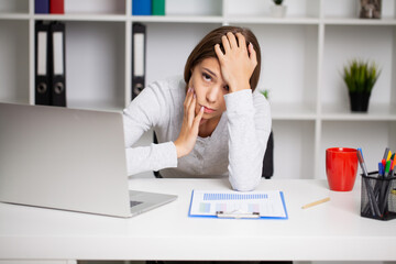Beautiful exhausted woman in the office suffering from severe toothache
