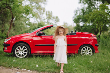Ukrainian beautiful 7 year old girl on red cabriolet.