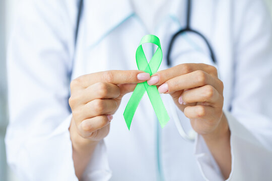 Green ribbon in hand as a symbol to awareness Lymphoma cancer