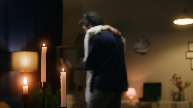 Young couple dancing in living room in evening. Romantic relationships and love. Happy woman and man hugging and enjoying slow dance at home, celebrating anniversary with candles.