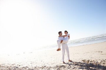 Keeping her close to himself. Full length shot of a young man carrying his girlfriend along a beach.