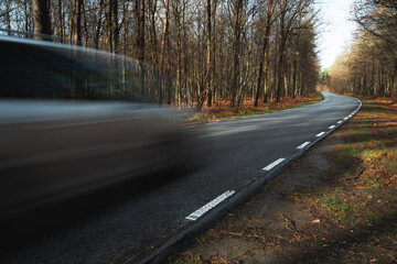 A car driving fast on a road through the forest