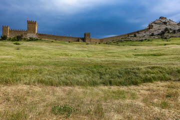 A picturesque view with a stormy sky of the Fortress Mountain and the ancient fortress. Genoese Fortress, Sudak, Crimea