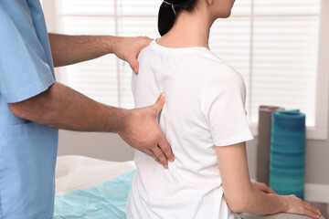 Orthopedist examining woman's back in clinic, closeup. Scoliosis treatment - obrazy, fototapety, plakaty