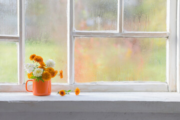 autumn flowers in orange cup on old white windowsill