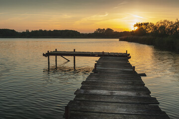 Sunset over a quiet lake with a pier