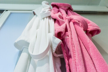 Two towelling bathrobes hanging on a door