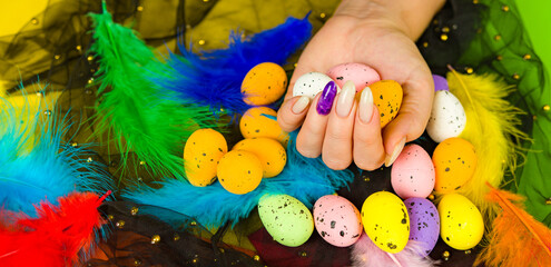Young woman's hand with manicure holds easter eggs. Unrecognizable person with multicolored easter eggs in spots.