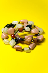 Necklace made of natural stone on a yellow background. Vertical view. Selective focus.