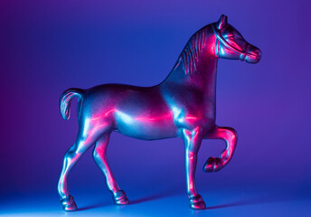 Obraz na płótnie Canvas Horse figurine with neon blue and pink illumination background. Future warfare conceptual backdrop.