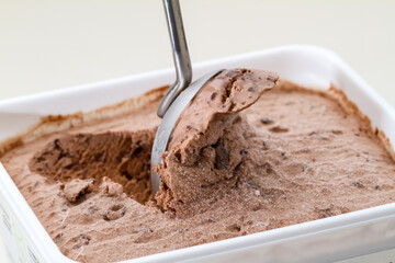 Scoop serving chocolate ice cream from a tub