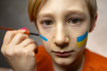 a child against war, a boy with a painted flag of Ukraine on his cheeks