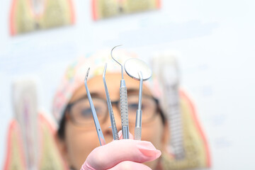 Dental instruments held by the hand of a dentist wearing pink gloves as she shows them to the...