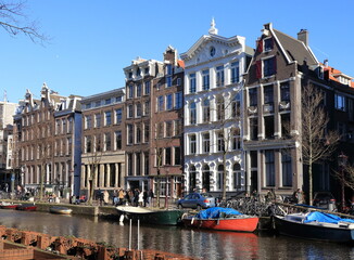Naklejka premium Amsterdam Kloveniersburgwal Canal View with Historic House Facades, Boats and People, Netherlands