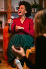 An African woman sitting at home, singing and having karaoke night.