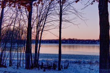 Tranquil landscape at the beginning of winter with the river partly frozen and bare trees