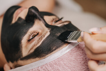 A carbon-based gel is applied to the skin of the girl's face with a brush for the carbon peeling procedure.