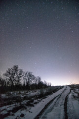 snowy landscape  forest in the night . Night landscape. Nightsky and clouds . Stars in the sky . Lights of the city . 