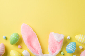 Fototapeta na wymiar Top view of pastel multicolored Easter eggs quail ones and fluffy headband in shape of rabbit ears situated on the isolated yellow background copyspace