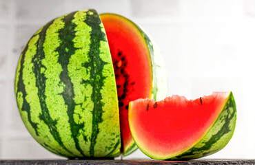 The concept of natural agricultural products. Ripe fresh watermelon and a piece of berry on a slate board on a light background. Close up of vegetarian food.