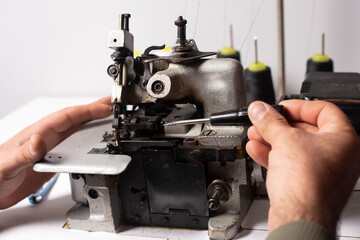 skilled mechanic repairing industrial sewing machine in factory