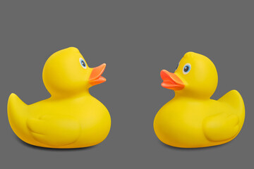 Two yellow rubber ducks on a gray background.