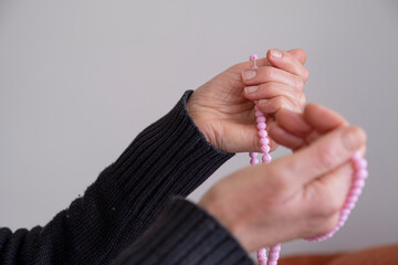 Selective focused praying hands of muslim woman with pink rosary.