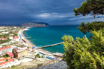 Naklejka premium Crimea - May 2021. A line of beaches in the city of Sudak. View from the Genoese fortress on the Sudak Bay. Russia.
